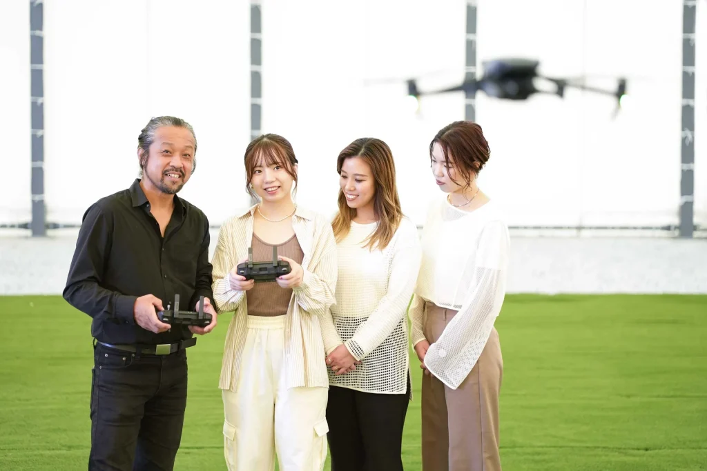 ドローンを飛ばす生徒とエミュドローンアカデミーのインストラクター